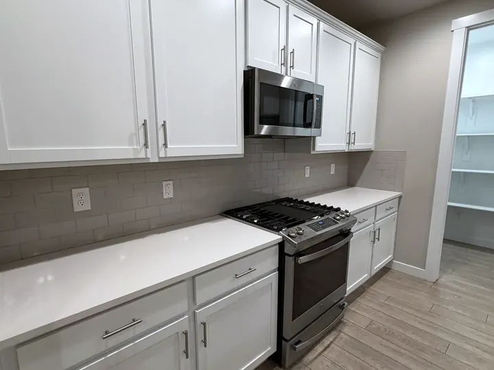 A clean kitchen with white cabinets and a stainless range